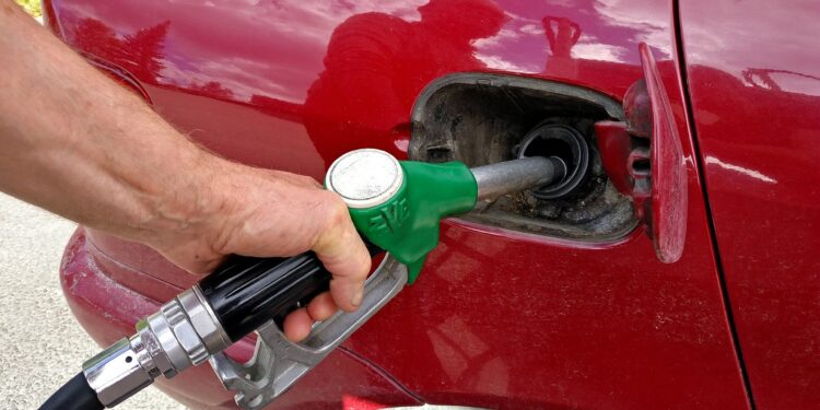 Bico de combustível inserido no tanque de um automóvel durante abastecimento em posto