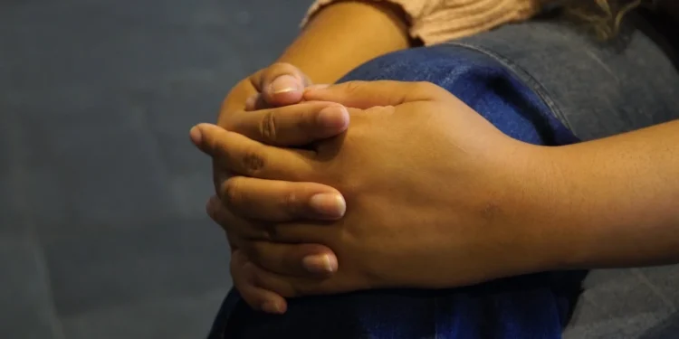 Mulher com as mãos unidas durante atendimento de acolhimento