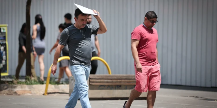 Pedestres caminham sob sol forte em São Paulo durante período de calor e baixa umidade