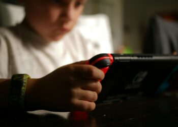 Criança segura dispositivo digital, imagem ilustrativa para matéria sobre recursos de segurança e controle parental