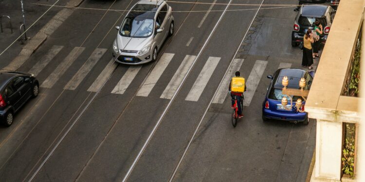 Entregador de comida circula de bicicleta em rua urbana, imagem ilustrativa para matéria sobre investimentos do iFood
