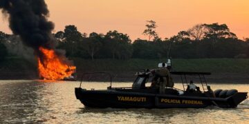 Embarcação da Polícia Federal navega no Rio Madeira enquanto uma draga usada no garimpo ilegal é destruída