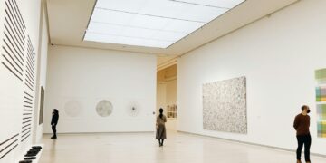 Visitantes observando obras de arte em uma galeria de museu