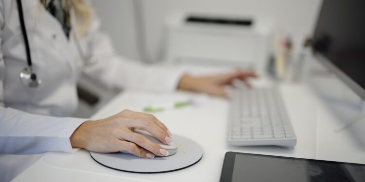 Profissional de saúde utiliza computador em consultório, imagem ilustrativa de serviços digitais